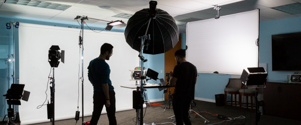 Alexis Mendez and Alex Stoica from Coldea Productions setting up a shoot to film a Blue-White Peristaltic Metering Pump in a professional studio setting.