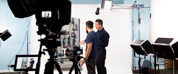 Coldea Productions team members Alexis Mendez and Alex Stoica conduct a professional video shoot for a Blue-White Peristaltic Metering Pump. The setup showcases Coldea Productions' expertise in capturing industrial equipment with high-quality lighting and camera work, enhancing product visibility for Blue-White Industries.
