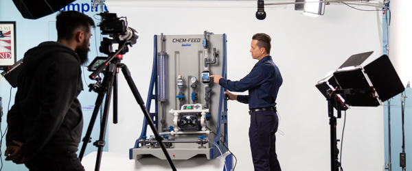 Rob Gledhill of Blue-White Industries demonstrates the features of a Plastic Chemical Feed Skid, with Alexis Mendez from Coldea Productions capturing the video for a product presentation.