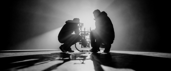 Two videographers working with a camera in a dimly lit, dramatic setting, ideal for video production companies in Phoenix, AZ, by Coldea Productions.