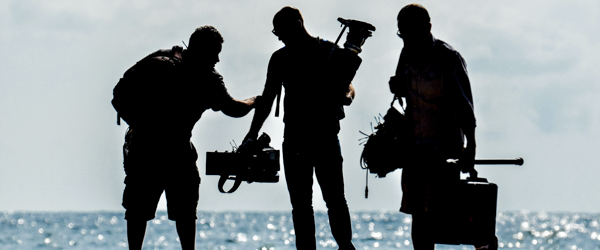 Coldea Productions film crew working outdoors by the sea, preparing video production equipment.