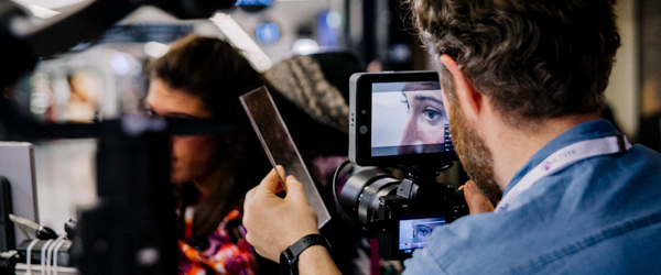 Close-up shot of a videographer filming a subject’s eye using a professional camera.