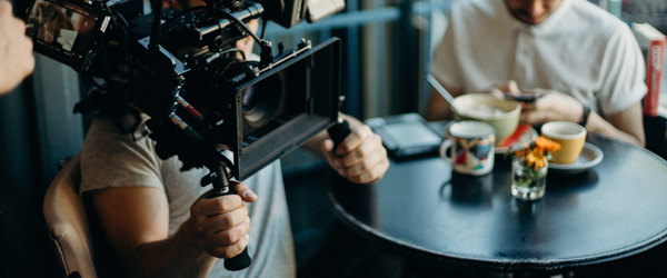 Cinematographer filming a casual cafe scene with professional equipment, ideal for video production services for production companies in Arizona, by Coldea Productions.