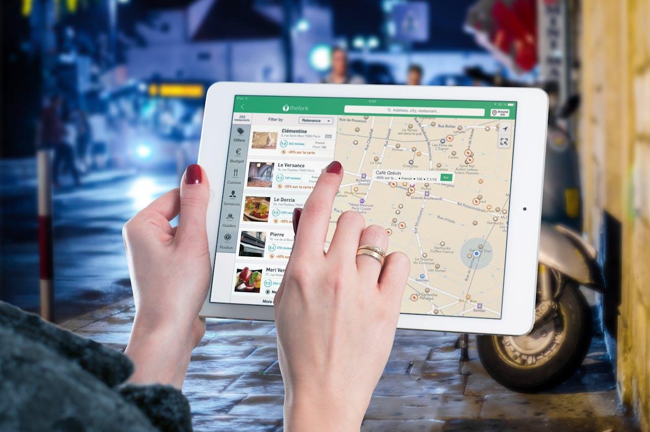 Person using a tablet to explore restaurant locations on a digital map, symbolizing the use of video marketing to announce a new business location.
