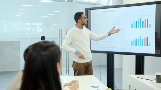 Business professional presenting analytics and growth charts during a meeting to illustrate data visualization in storytelling.